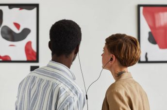 Ein Paar steht in einem Museum vor einem Bild und teilt sich Kopfhörer